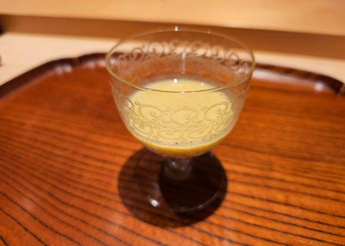 Chilled sweet corn soup, served in an ornate glass.